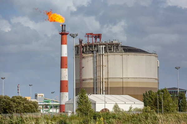 Vista de la planta de refinería de petróleo con su chimenea en llamas contra el cielo azul —  Fotos de Stock