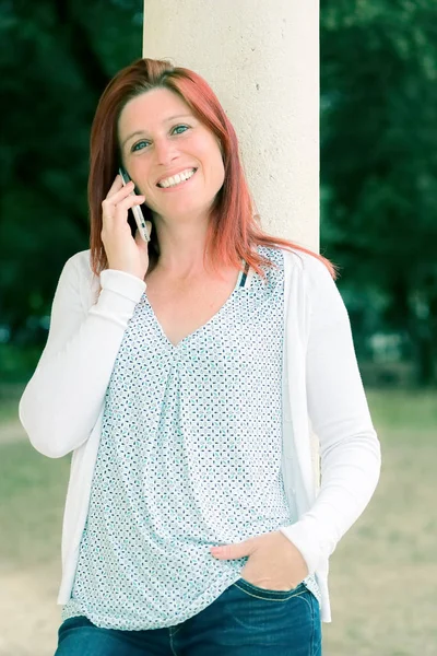 Cut smiling redheaded woman making a call with her cell phone — Stock Photo, Image