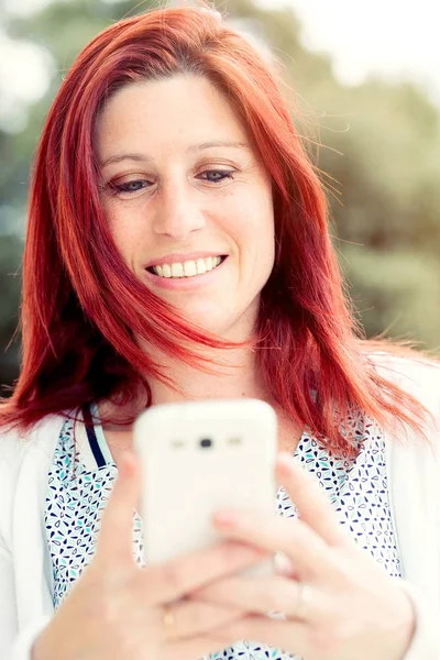 मुस्कुराते सुंदर युवा महिला मोबाइल फोन के साथ करीब, अगेंस्टिन — स्टॉक फ़ोटो, इमेज