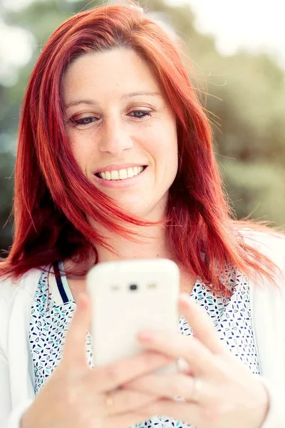 Smiling beautiful young woman close up with mobile phone, agains — Stock Photo, Image