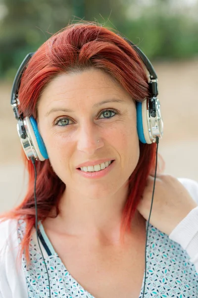 Retrato de una atractiva pelirroja sonriente escuchando a mus — Foto de Stock