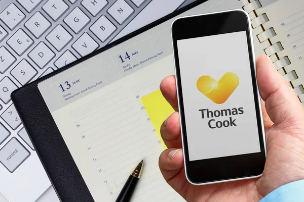 Ofisteki adam, Thomas Cook Havayolları'nın compagny'si hakkında bilgi almak için akıllı telefonlarını kullanıyor. Thomas cook Airlines logosu bir akıllı telefonun ekranında görüntülenir. — Stok fotoğraf