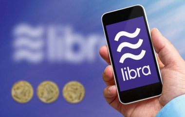 Terazi logosu ile elinde bir akıllı telefon tutan adam, facebook şirketi tarafından oluşturulan yeni kripto para birimi