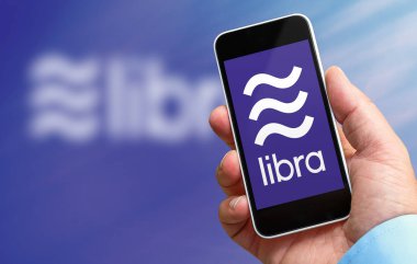 Terazi logosu ile elinde bir akıllı telefon tutan adam, facebook şirketi tarafından oluşturulan yeni kripto para birimi
