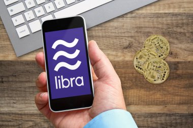Terazi logosu ile elinde bir akıllı telefon tutan adam, facebook şirketi tarafından oluşturulan yeni kripto para birimi