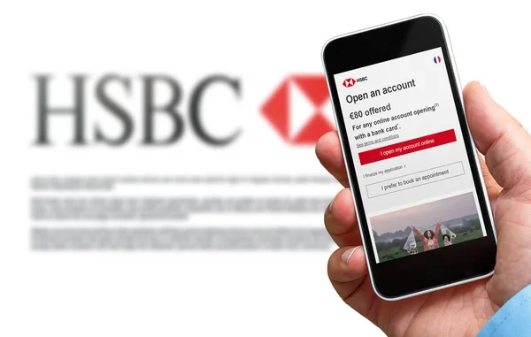 Homem segurando um smartphone em sua mão com hsbc página de sinalização francesa. Logotipo HSBC desfocado do site em segundo plano — Fotografia de Stock