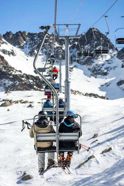 Nierozpoznane osoby jadące kolejką górską po śnieżnym zboczu góry — Zdjęcie stockowe