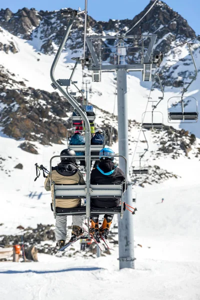Nepoznatelní lidé jezdí lanovkou přes zasněžený svah hory — Stock fotografie
