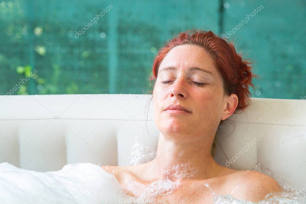Portrait of Pretty natural redheaded woman relaxing in her jacuzzi