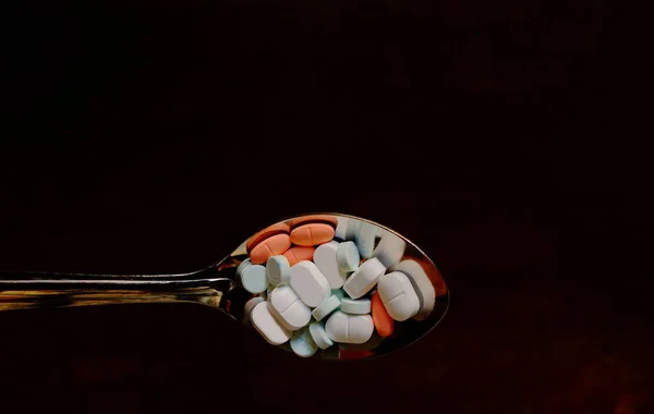 çok fazla uyuşturucu hap üzerinde koyu kahverengi ahşap yüzey, paslanmaz kaşık içinde portre görüntülerinin kullanımını çok fazla uyuşturucu kavramı