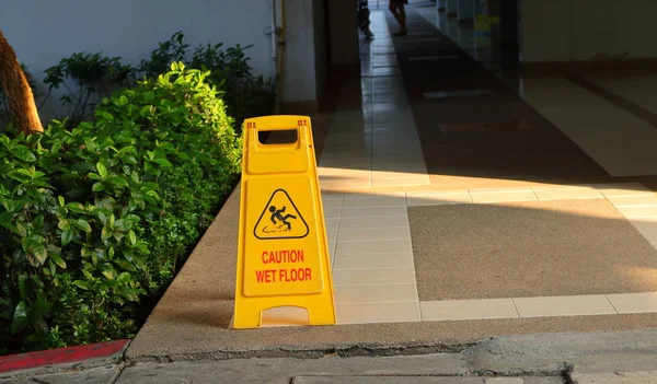 特写图片的旧黄色警告标志读谨慎潮湿的地板上 在一个建筑的人行道上 — 图库照片