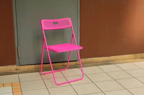 Closeup Cadeira Dobrável Rosa Quente Vazio Colocado Frente Porta Cinza — Fotografia de Stock