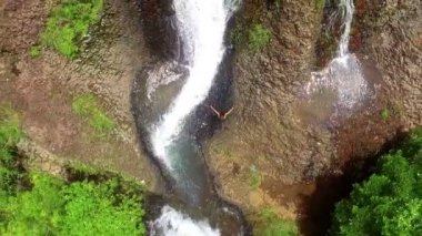 Kollarını bir şelale havadan görünümü yanındaki yükselterek bir kadın. Harika bozulmamış şelale hava dikey dron görünümü. Amerikan Karayipler nehir cascade yağmur ormanlarında.