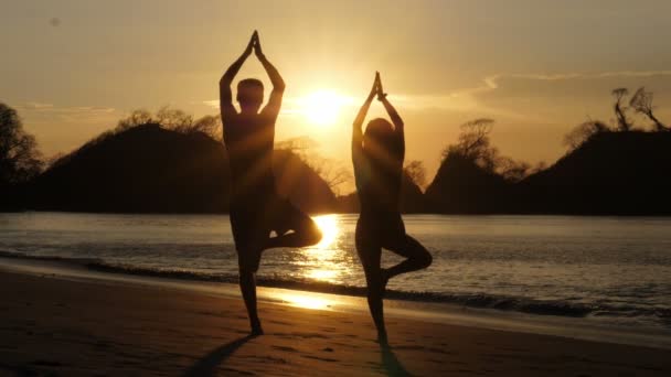 Pareja Joven Practicando Yoga Playa Atardecer Pareja Haciendo Ejercicio Una — Vídeo de stock