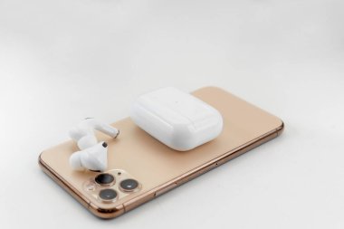Bir cep telefonunun yanında beyaz kablosuz kulaklık.