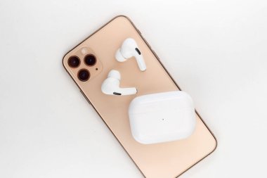 Bir cep telefonunun yanında beyaz kablosuz kulaklık.