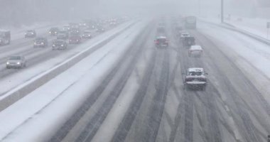 Karla kaplı bir yolda giden arabalar