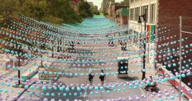 Montreal, Quebec, Kanada - 23 Ağustos 2018: Turistler ve yerel halk yaz boyunca Montreal Quebec Kanada 'nın eşcinsel köyünde Saint Catherine Caddesi boyunca yürüdüler. Bütün cadde boyunca çok renkli toplar süslemede asılı..