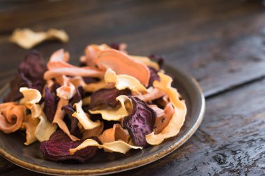 Koyu ahşap arka plan, kopya alanı üzerinde çeşitli sebze cips. Çeşitli kurutulmuş pancar, havuç, kabak sebze cips - sağlıklı vegan snack.