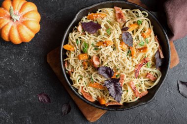 Kabak ve dökme demir tavada pastırma ile sonbahar makarna. Ev yapımı spagetti kabak pasta pastırma, parmesan peyniri ve fesleğen siyah, kopya alanı ile. Sonbahar gıda.