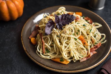 Kabak ve plaka üzerinde pastırma ile sonbahar makarna. Ev yapımı spagetti kabak pasta pastırma, parmesan peyniri ve fesleğen siyah, kopya alanı ile. Sonbahar gıda.