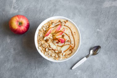 Elmalı turta güler yüzlü kase. Elma, tarçın, badem sütü, yulaf granola, tuzlu karamel ve baharatlar, üstten görünüm, kopya alanı ile güler yüzlü kase kahvaltı.
