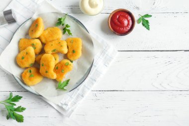 Tavuk nuggets ve beyaz ahşap zemin, kopya alanı üzerine sos. Fried nuggets ketçap ve mayonez ile.