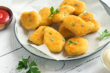 Tavuk nuggets ve beyaz ahşap zemin, kopya alanı üzerine sos. Fried nuggets ketçap ve mayonez ile.