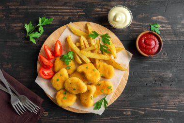 Tavuk nuggets, patates kızartması ve koyu ahşap arka plan üzerinde soslar alanı kopyalayın. Fried nuggets ve ketçap ve mayonez ile patates.