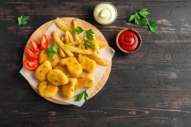 Tavuk nuggets, patates kızartması ve koyu ahşap arka plan üzerinde soslar alanı kopyalayın. Fried nuggets ve ketçap ve mayonez ile patates.