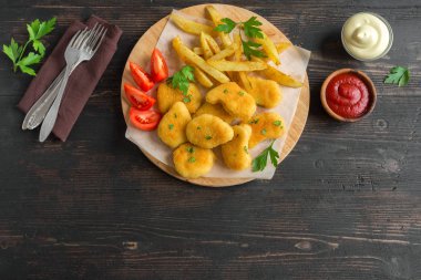 Tavuk nuggets, patates kızartması ve koyu ahşap arka plan üzerinde soslar alanı kopyalayın. Fried nuggets ve ketçap ve mayonez ile patates.