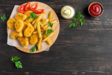 Tavuk nuggets, patates kızartması ve koyu ahşap arka plan üzerinde soslar alanı kopyalayın. Fried nuggets ve ketçap ve mayonez ile patates.