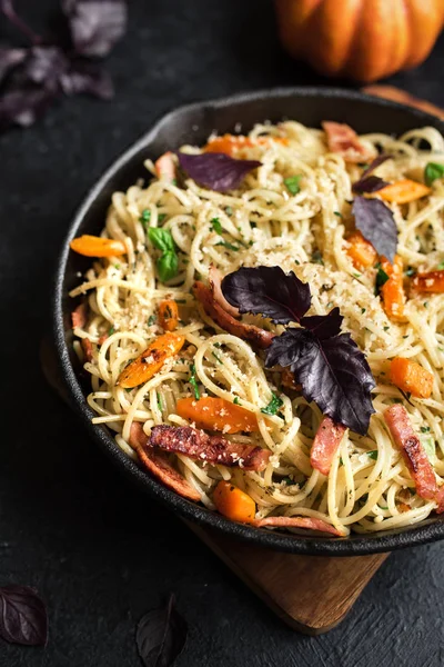Kabak ve dökme demir tavada pastırma ile sonbahar makarna. Ev yapımı spagetti kabak pasta pastırma, parmesan peyniri ve fesleğen siyah, kopya alanı ile. Sonbahar gıda.