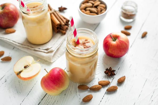 Apple pie protein smoothie drink with almond milk. Homemade apple smoothie with apple pie spices (cinnamon) on white wooden background.