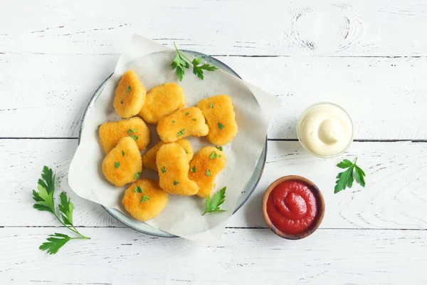 Tavuk nuggets ve beyaz ahşap zemin, kopya alanı üzerine sos. Fried nuggets ketçap ve mayonez ile.