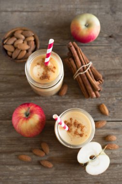 Elmalı turta protein güler yüzlü badem sütü içkiyle. Ahşap zemin, üstten görünüm üzerine elmalı turta baharat (Tarçın) ile ev yapımı elma güler yüzlü.