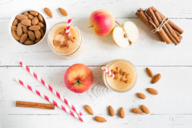 Elmalı turta protein güler yüzlü badem sütü içkiyle. Beyaz ahşap zemin, kopya alanı üzerine elmalı turta baharat (Tarçın) ile ev yapımı elma güler yüzlü.