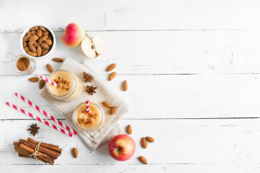 Elmalı turta protein güler yüzlü badem sütü içkiyle. Beyaz ahşap zemin, kopya alanı üzerine elmalı turta baharat (Tarçın) ile ev yapımı elma güler yüzlü.