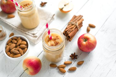 Elmalı turta protein güler yüzlü badem sütü içkiyle. Beyaz ahşap zemin, kopya alanı üzerine elmalı turta baharat (Tarçın) ile ev yapımı elma güler yüzlü.