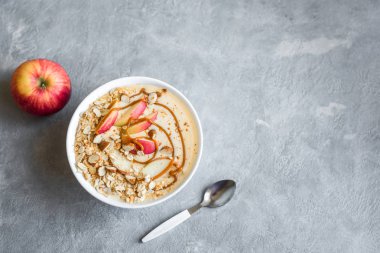 Elmalı turta güler yüzlü kase. Elma, tarçın, badem sütü, yulaf granola, tuzlu karamel ve baharatlar, üstten görünüm, kopya alanı ile güler yüzlü kase kahvaltı.