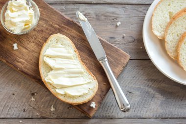 Top görünümü tereyağı ve rustik ahşap arka plan üzerinde bıçak ile kahvaltıda ekmek