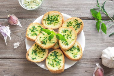 Sarımsak ve malzemelerle ahşap arka plan, kopya alanı üzerinde otlar ile kızarmış ekmek.