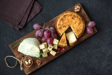 Peynir tabağı ile çeşitli peynirler, üzüm, fındık siyah arka plan, kopya alanı üzerinde. İtalyan peynir ve meyve tabağı.