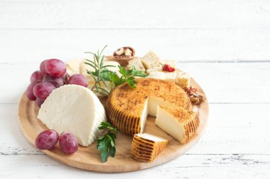 Peynir tabağı ile çeşitli peynirler, üzüm, fındık Beyaz ahşap arka plan, kopya alanı üzerinde. İtalyan peynir ve meyve tabağı.