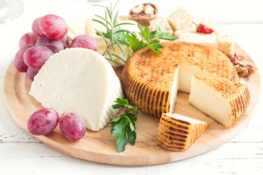 Peynir tabağı ile çeşitli peynirler, üzüm, fındık Beyaz ahşap arka plan, kopya alanı üzerinde. İtalyan peynir ve meyve tabağı.