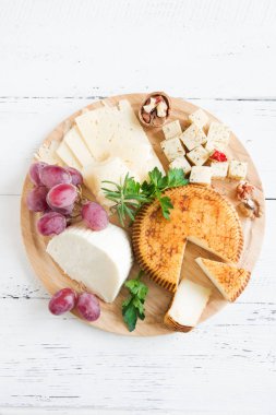 Peynir tabağı ile çeşitli peynirler, üzüm, fındık Beyaz ahşap arka plan, kopya alanı üzerinde. İtalyan peynir ve meyve tabağı.