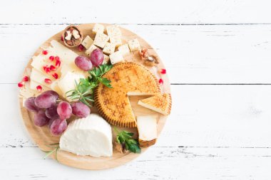 Peynir tabağı ile çeşitli peynirler, üzüm, fındık Beyaz ahşap arka plan, kopya alanı üzerinde. İtalyan peynir ve meyve tabağı.