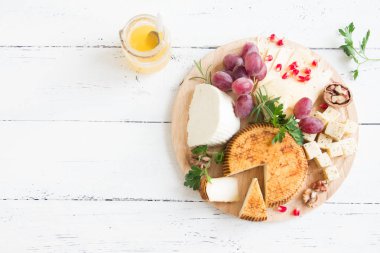 Peynir tabağı ile çeşitli peynirler, üzüm, fındık Beyaz ahşap arka plan, kopya alanı üzerinde. İtalyan peynir ve meyve tabağı.