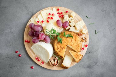 Peynir tabağı ile çeşitli peynirler, üzüm, fındık gri taş zemin, kopya alanı üzerinde. İtalyan peynir ve meyve tabağı.