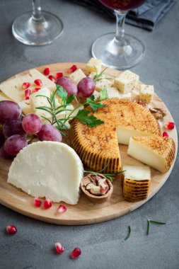 Peynir tabağı ile çeşitli peynirler, üzüm, fındık gri taş zemin, kopya alanı üzerinde. İtalyan peynir ve meyve tabağı.